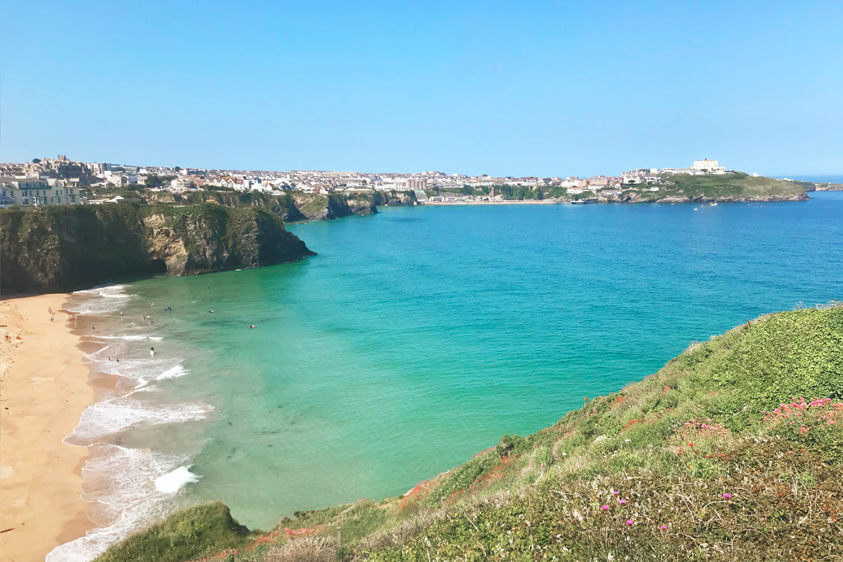 A view of Newquay beaches shot from Tolcarne cliffs on a sunny day