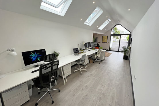 The Oracle Design Studio in Newquay. Showing 3 desks with PCs and chairs.